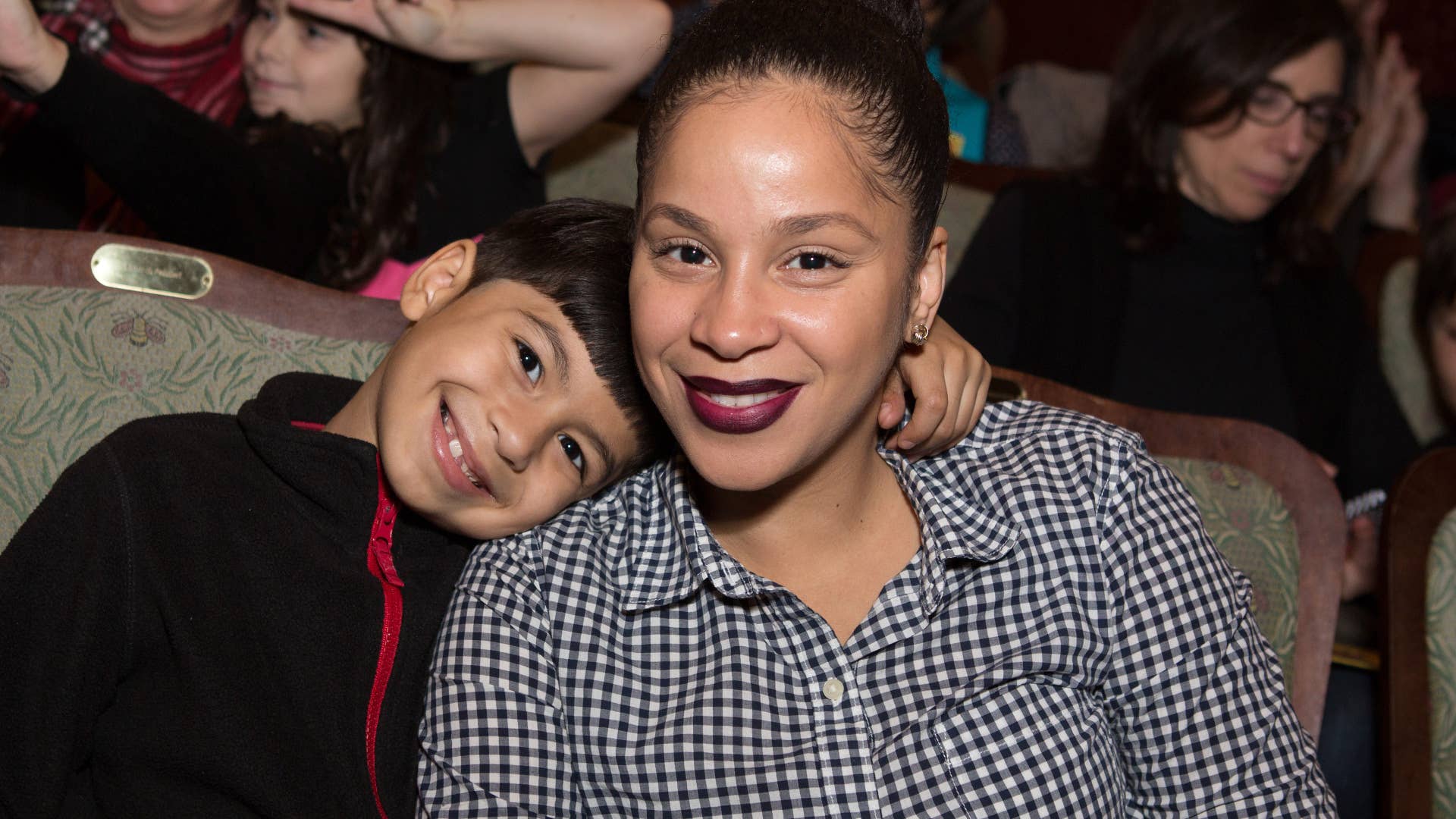 A child resting his head on the shoulder of a women.